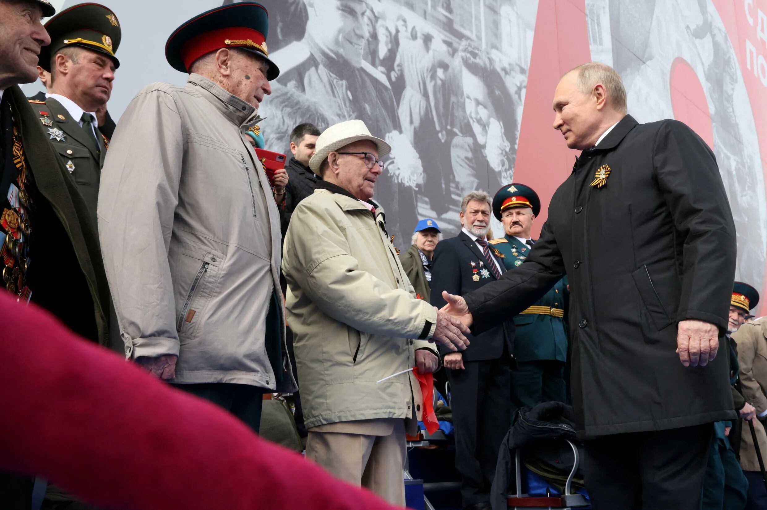 El presidente ruso, Vladímir Putin, estrecha la mano a los espectadores antes de un desfile militar en el Día de la Victoria, que marca el 77º aniversario de la victoria sobre la Alemania nazi en la Segunda Guerra Mundial, en la Plaza Roja en el centro de Moscú, Rusia, el 9 de mayo de 2022. 