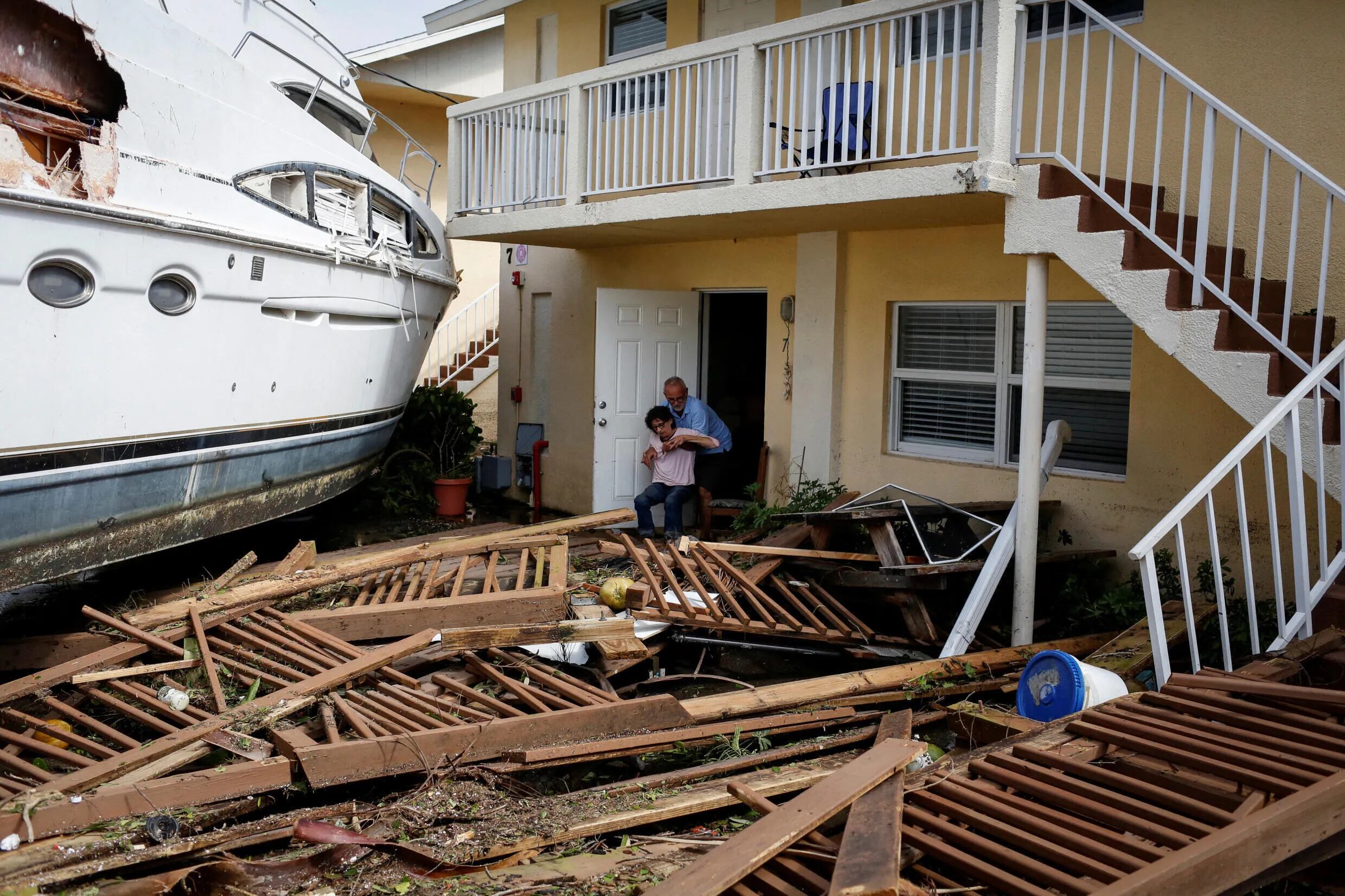 Un hombre ayuda a una mujer junto a un barco dañado en medio de un condominio del centro de la ciudad después de que el huracán Ian causara una amplia destrucción, en Fort Myers, Florida, Estados Unidos, el 29 de septiembre de 2022.